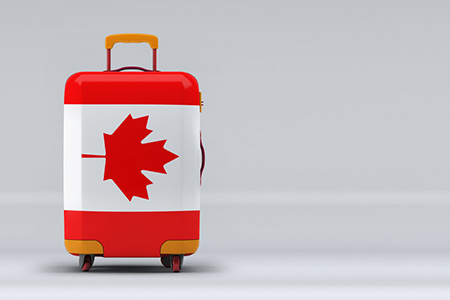 Canada national flag on a stylish suitcases on color background. Space for text. International trave