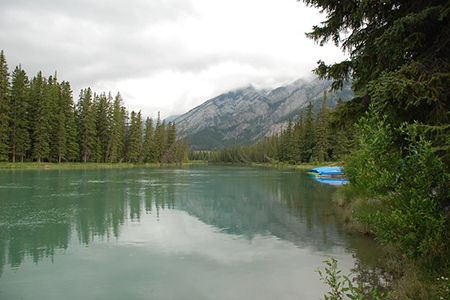 View of water and mountains under cloudy sky - banff
