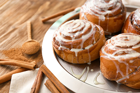 Plate with tasty cinnamon buns on wooden table, closeup
