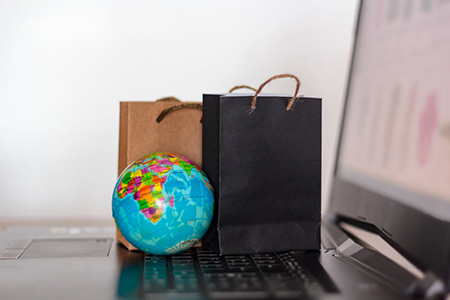 Shopping bags and world globe on laptop keyboard. Worldwide online shopping, e-commerce concept
