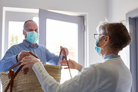 Groceries delivery to senior citizens with face mask in home quarantine for Covid-19 coronavirus