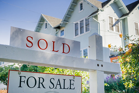 Sold sign in front of a house in a residential neighborhood
