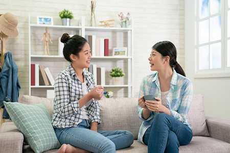 Two friends talking with coffee mugs on couch