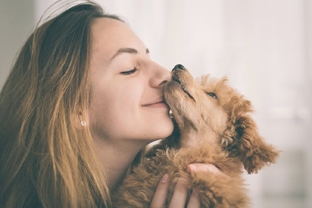Young woman kissing her dog