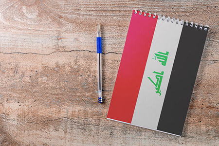 Notepad with Iraq flag, pen on wooden background