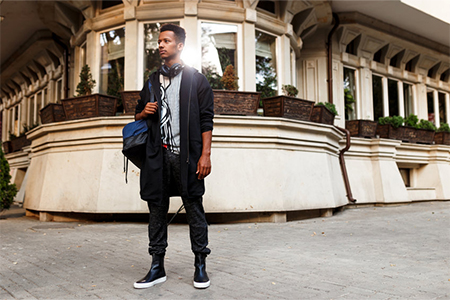 Portrait of male model in casual clothes poses confident on street during buildings. Traveler in new