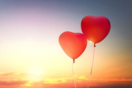 two red balloons in shape of heart on the background of sunset sky. the concept of love and Valentin