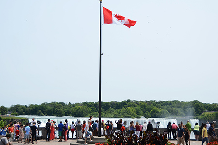 canada flag and group of people standing at Niagara falls