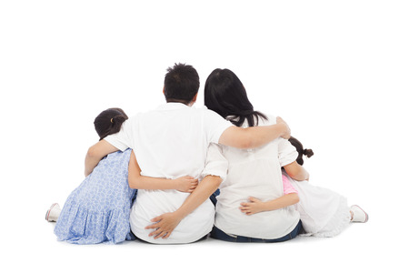 back view of family of four hugging. two children, two parents in centre