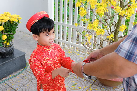 Grandfather giving lucky money to grandson on the first day of Vietnamese lunar new year Tet