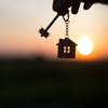 Silhouette of a house figure with a key, a pen with a keychain on the background of the sunset. They