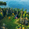 Aerial top view of red log cabin or cottage with sauna in spring forest by the lake in rural Finland