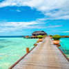 Wooden bridge leading to an exotic bungalow on the background of azure water, maldives
