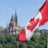 Canadian flag waving with Parliament Buildings hill and Library in the background