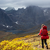 Woman backpacking on scenic hiking trail to lake surrounded by mountains during fall in canadian nat