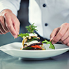 Chef in Restaurant garnishing vegetable dish, crop on hands, filtered image
