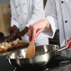 Close-up view of female chef cooking on frying pan