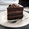 Plate with piece of delicious chocolate cake on wooden table