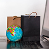Shopping bags and world globe on laptop keyboard. Worldwide online shopping, e-commerce concept