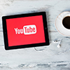 red YouTube splash screen on tablet. Tablet and coffee on table