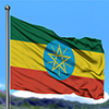 Ethiopia flag waving in the blue sky with green fields at mountain peak background. Nature theme.