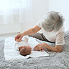 Grandmother admires her sweet granddaughter. Great-grandmother plays with a newborn great-granddaugh