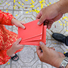 man handing red envelope to woman - top, cropped view of hands only