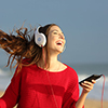 Happy girl wearing red colorful jersey dancing singing and listening music on line with headphones f