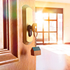 Open entrance door detail of a house with keys in the lock and empty room in the background with gol