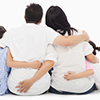 back view of family of four hugging. two children, two parents in centre
