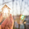 person holding small house-shaped block