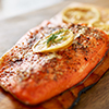 cooked salmon fillet on wooden cedar plank with lemon slices and dill