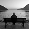 Elderly man sitting alone near lake