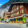 Principal street of Lauterbrunnen with shops,hotels,terraces,swiss flags and stunning Staubbach wate
