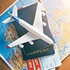 stacked items: map, passport, boarding passes, miniature airplane