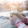 Side view of female hand holding hot cup of coffee in winter