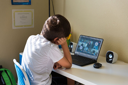 Boy student having a video call with his classmates in elementary school during covid-19 school shut