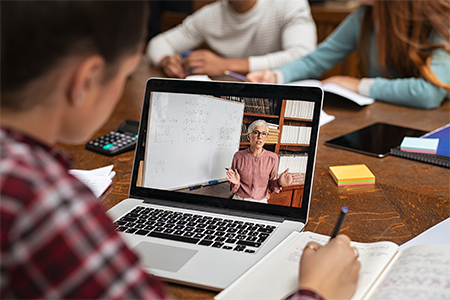 Rear view of university student understanding concepts online while making notes