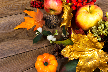 background with apples, golden and orange maple leaves, rowan and white berries on the wooden table