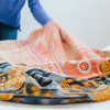 A person spreading a quilt fabric over a bed in a bedroom