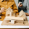 Two colleagues discussing architectural project at construction site at desk in office
