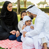 Happy middle-eastern family having fun in a park- Parents and kids celebrating summer in the nature
