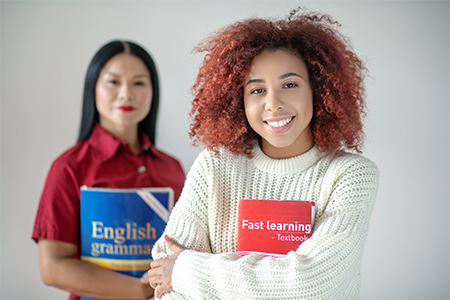 Curly red-haired woman holding English learning book