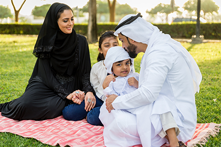 Happy middle-eastern family having fun in a park- Parents and kids celebrating summer in the nature