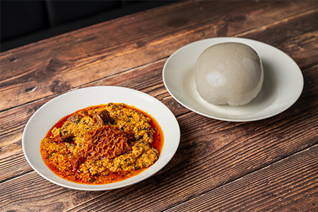 A plate of Nigerian cuisine served with pounded yam on a wooden table