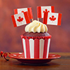 Red and white theme cupcakes with Canadian maple leaf flags for first of July Canada Day or Canadian
