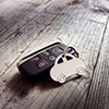 Car shape keyring and keyless entry remote on wood background