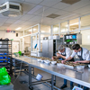Chefs preparing food in a commercial kitchen with stainless steel equipment