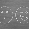 emoticons drawn in white chalk on a gray board