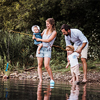 A young family with two toddler children spending time outdoors by the river in summer